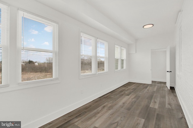 spare room with dark hardwood / wood-style floors and a healthy amount of sunlight