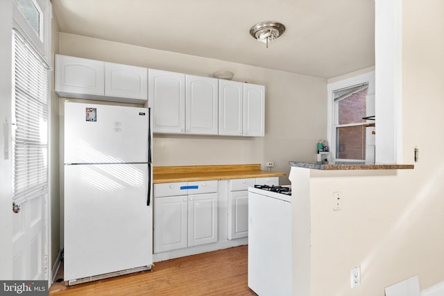 kitchen featuring light wood-type flooring, wood counters, white appliances, and white cabinets