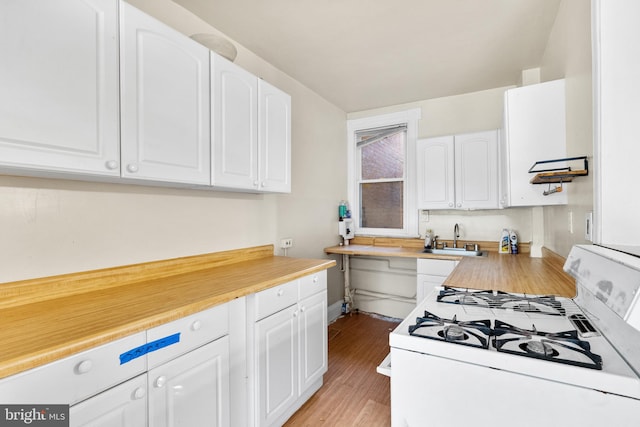 kitchen featuring white range with gas cooktop, sink, light hardwood / wood-style flooring, and white cabinets