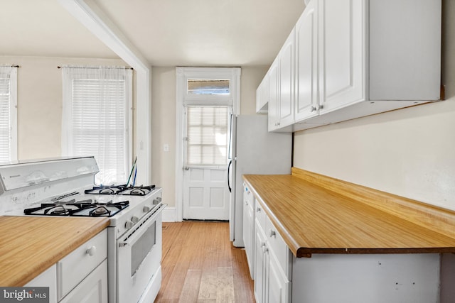 kitchen with white appliances, light hardwood / wood-style floors, white cabinets, and wood counters