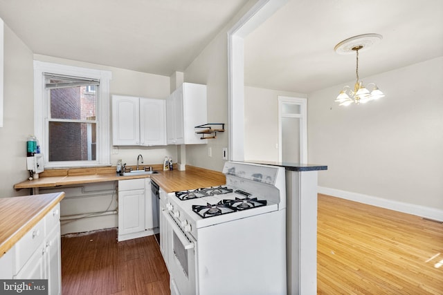 kitchen with dark hardwood / wood-style flooring, kitchen peninsula, white cabinetry, white range with gas stovetop, and decorative light fixtures