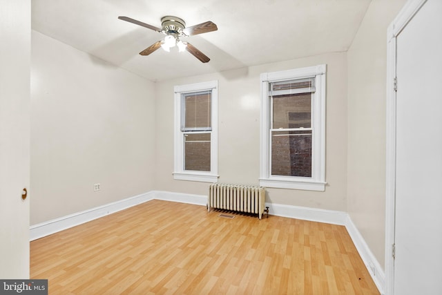 unfurnished room with light wood-type flooring, ceiling fan, and radiator heating unit