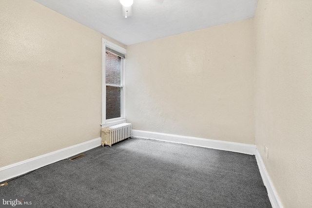 carpeted empty room featuring radiator heating unit