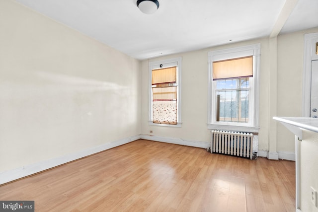 unfurnished room featuring radiator and light hardwood / wood-style floors