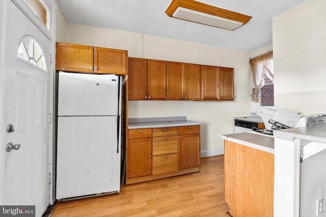 kitchen with kitchen peninsula, white fridge, and light hardwood / wood-style flooring