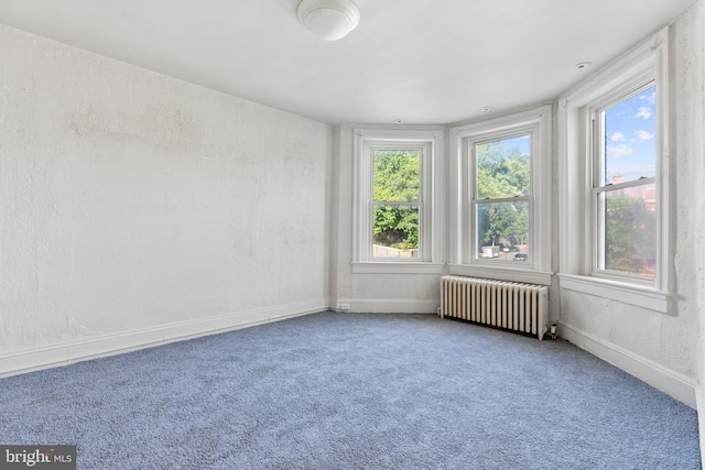 unfurnished room featuring radiator heating unit and carpet flooring