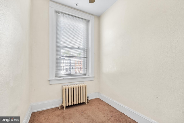 unfurnished room with radiator and light colored carpet