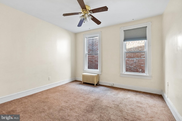 carpeted empty room featuring ceiling fan and radiator