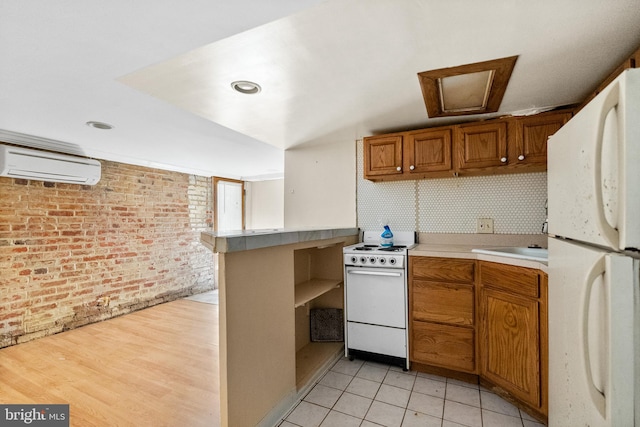 kitchen featuring light hardwood / wood-style floors, white appliances, brick wall, kitchen peninsula, and an AC wall unit