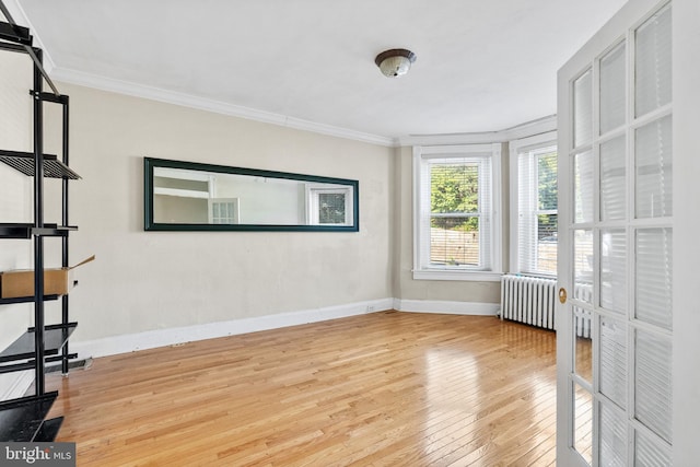 spare room featuring crown molding, radiator, and wood-type flooring