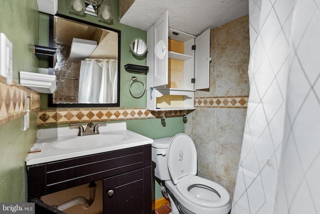 bathroom with vanity, tile walls, toilet, and a textured ceiling