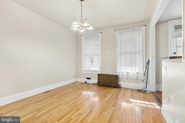 unfurnished dining area with wood-type flooring, radiator, and an inviting chandelier