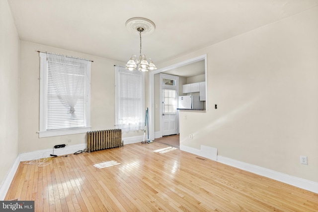 unfurnished dining area with radiator, a chandelier, and wood-type flooring