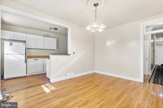 unfurnished dining area featuring a notable chandelier and light hardwood / wood-style floors