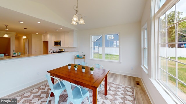 dining space with a notable chandelier, a wealth of natural light, and light wood-type flooring