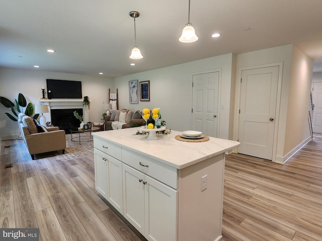 kitchen featuring light hardwood / wood-style floors, decorative light fixtures, a center island, and white cabinets