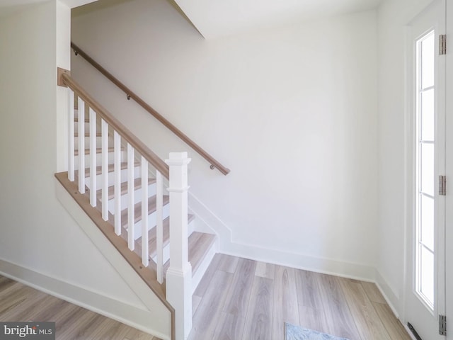 stairway with wood-type flooring and a wealth of natural light