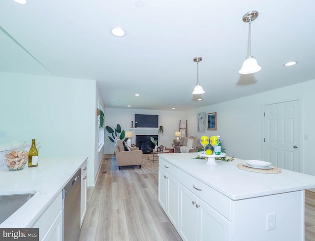 kitchen featuring a center island, white cabinetry, hanging light fixtures, light hardwood / wood-style flooring, and stainless steel dishwasher