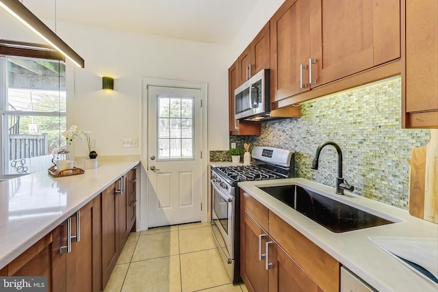 kitchen with hanging light fixtures, light tile patterned floors, sink, backsplash, and appliances with stainless steel finishes