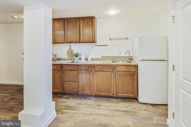 kitchen featuring sink, light hardwood / wood-style flooring, and white fridge