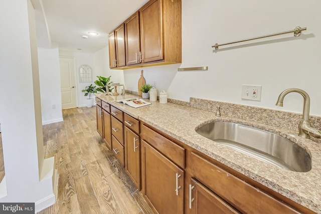 kitchen featuring light stone countertops, light hardwood / wood-style floors, and sink