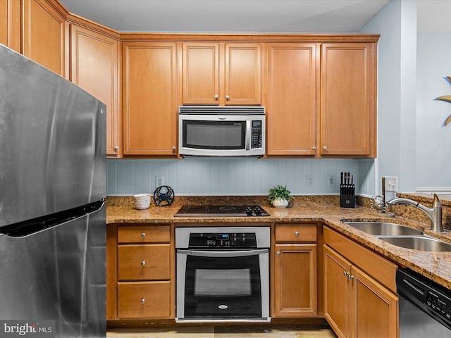 kitchen with light stone countertops, stainless steel appliances, and sink