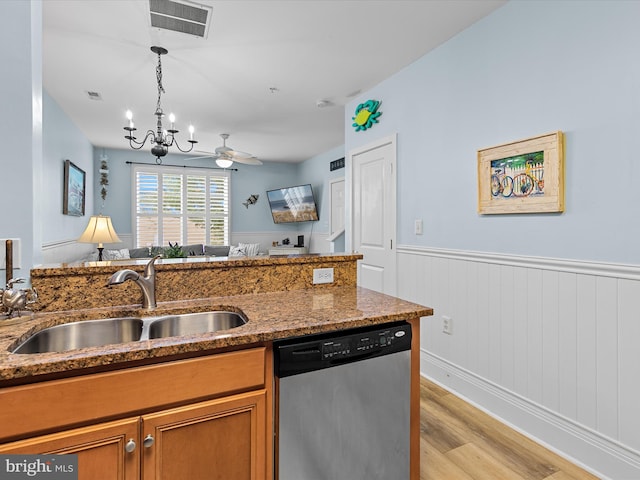 kitchen featuring light hardwood / wood-style floors, sink, decorative light fixtures, dark stone countertops, and stainless steel dishwasher