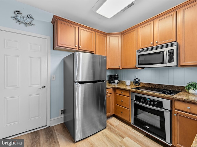 kitchen with light stone countertops, light wood-type flooring, and appliances with stainless steel finishes