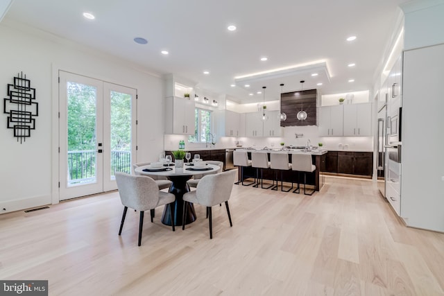 dining area featuring light wood-type flooring, crown molding, and french doors