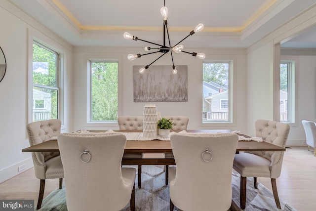 dining room with a raised ceiling, a chandelier, crown molding, and light hardwood / wood-style floors