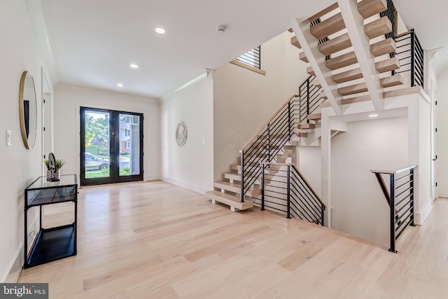 entryway featuring french doors, light hardwood / wood-style flooring, and crown molding