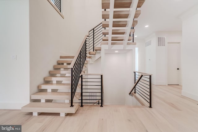 stairs with hardwood / wood-style floors and beamed ceiling