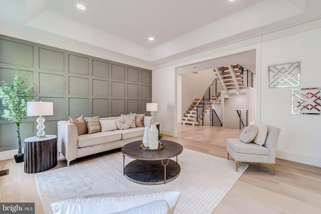 living room with a raised ceiling and light hardwood / wood-style flooring