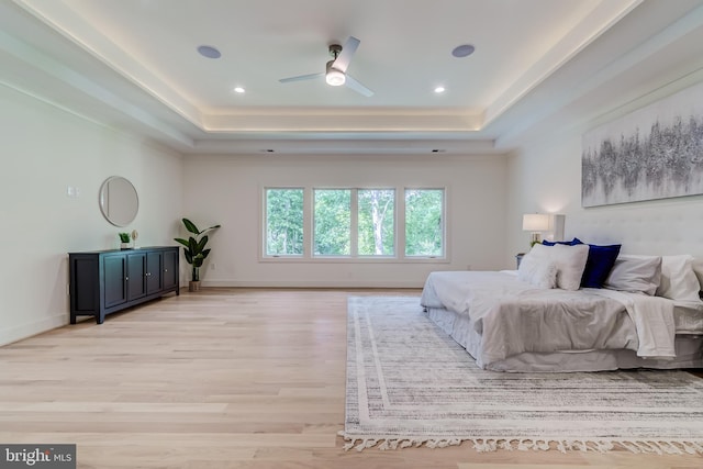 bedroom with ceiling fan, a raised ceiling, and light hardwood / wood-style flooring