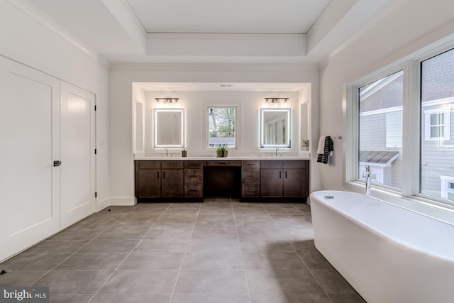 bathroom featuring vanity, tile patterned floors, a washtub, ornamental molding, and a tray ceiling