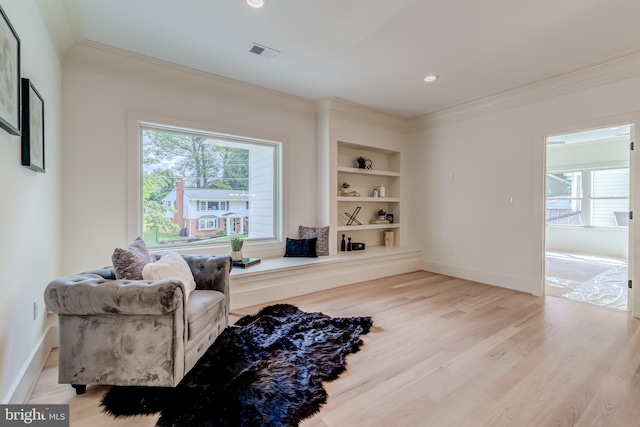 living area featuring built in features, light wood-type flooring, and crown molding