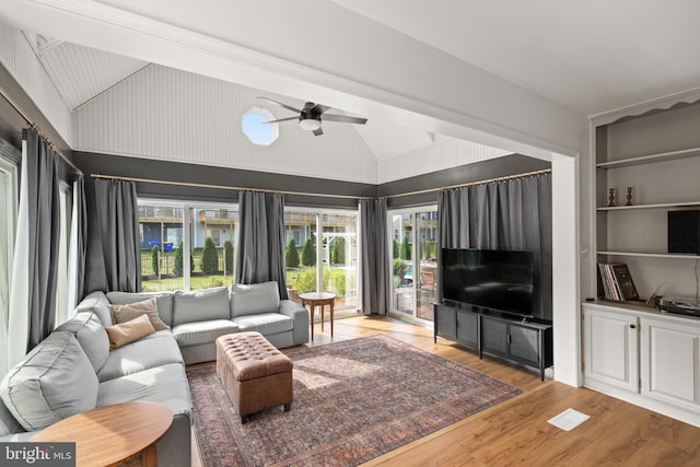 living room featuring ceiling fan, built in features, beam ceiling, wood-type flooring, and high vaulted ceiling