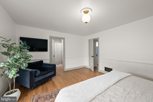 bedroom with connected bathroom and hardwood / wood-style floors