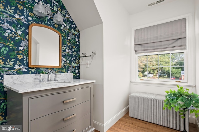 bathroom with vanity, vaulted ceiling, radiator, and hardwood / wood-style flooring