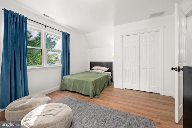 bedroom with wood-type flooring, lofted ceiling, and a closet