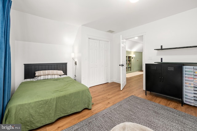 bedroom featuring vaulted ceiling, hardwood / wood-style floors, and a closet