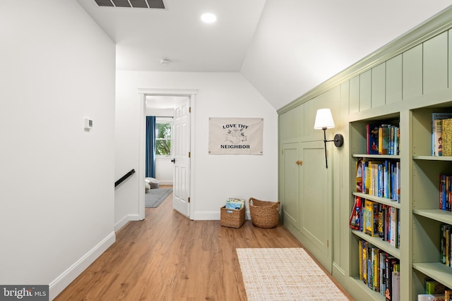 corridor featuring light hardwood / wood-style flooring and vaulted ceiling