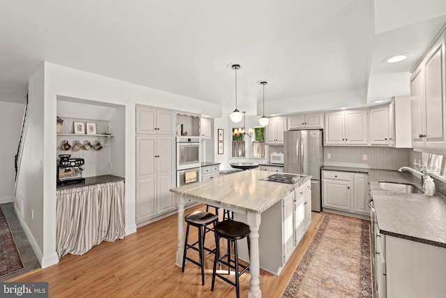 kitchen featuring light wood-type flooring, white cabinetry, a center island, and sink