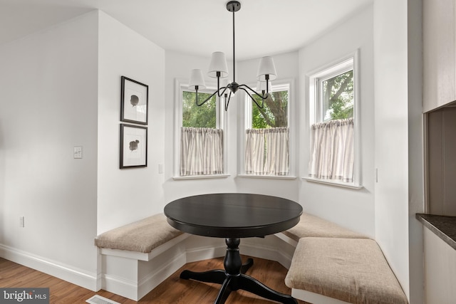 dining space with wood-type flooring, breakfast area, and a notable chandelier