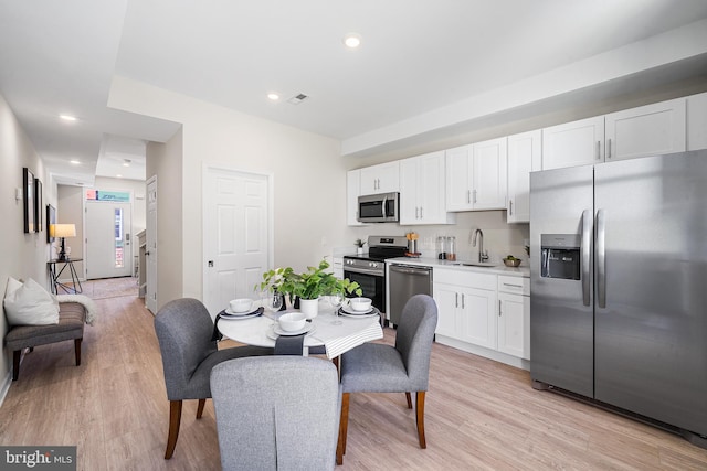 kitchen with white cabinets, appliances with stainless steel finishes, light wood-type flooring, and sink