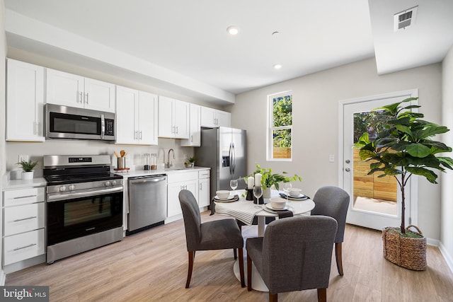 kitchen with light hardwood / wood-style flooring, white cabinetry, and appliances with stainless steel finishes