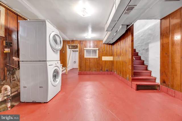 basement featuring stacked washer and dryer and wooden walls