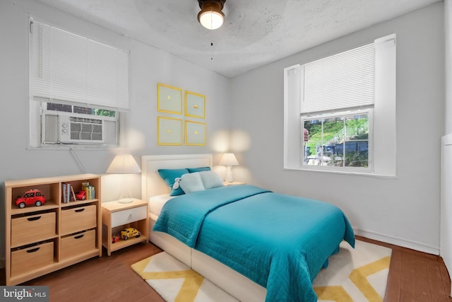 bedroom featuring a textured ceiling, cooling unit, and dark wood-type flooring