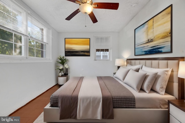 bedroom with a textured ceiling, hardwood / wood-style flooring, and ceiling fan