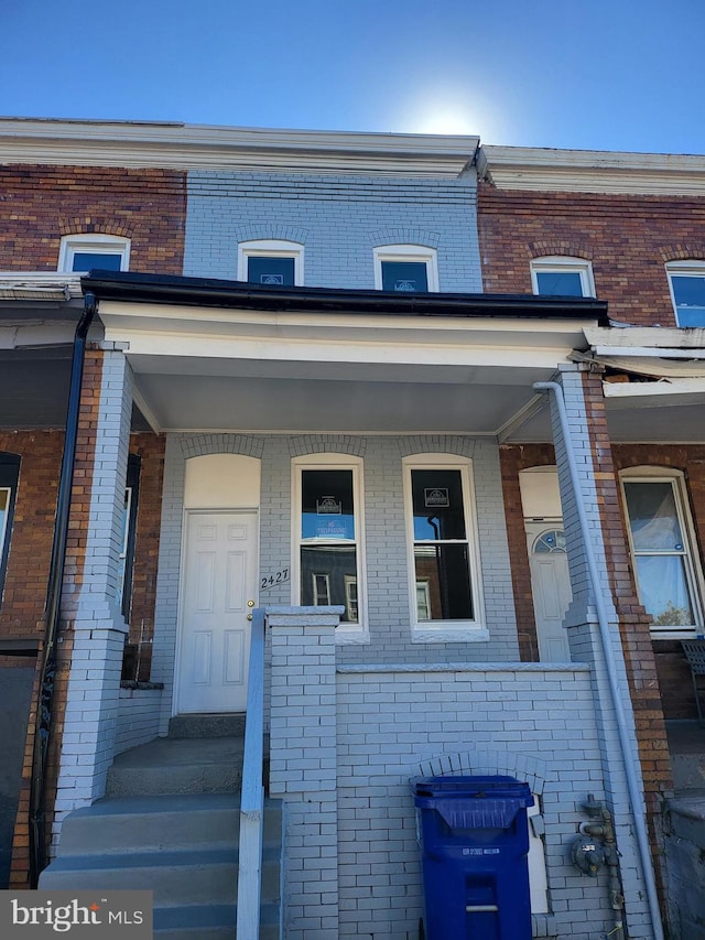property entrance with covered porch and brick siding